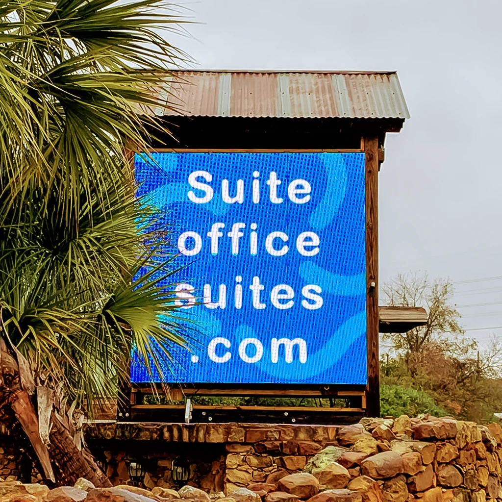 Full-color outdoor LED sign in direct sunlight on a stone monument base